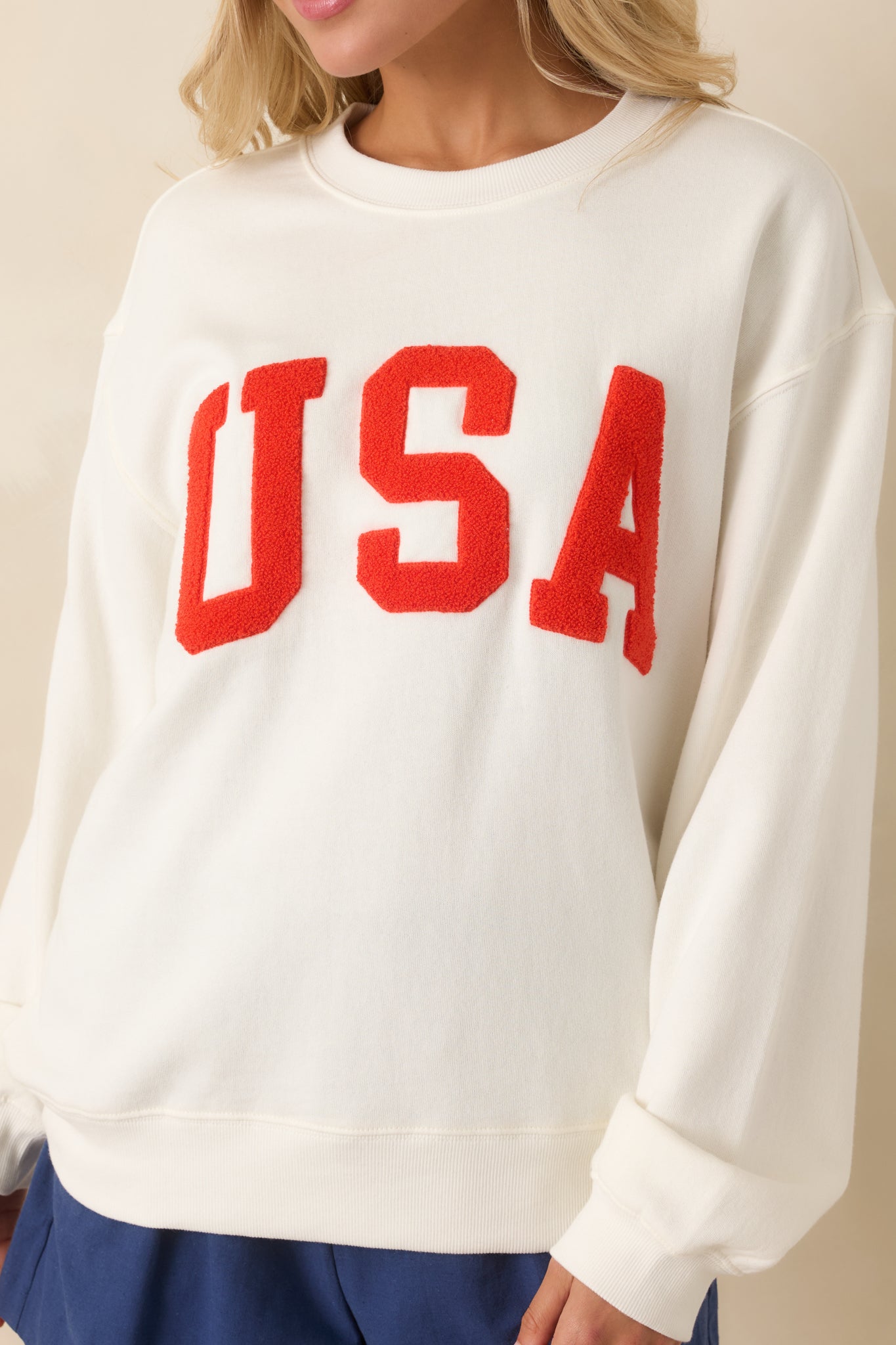 Tight detail of the “USA” lettering, showing its soft textured finish and subtle raised stitching against the woven cotton base.