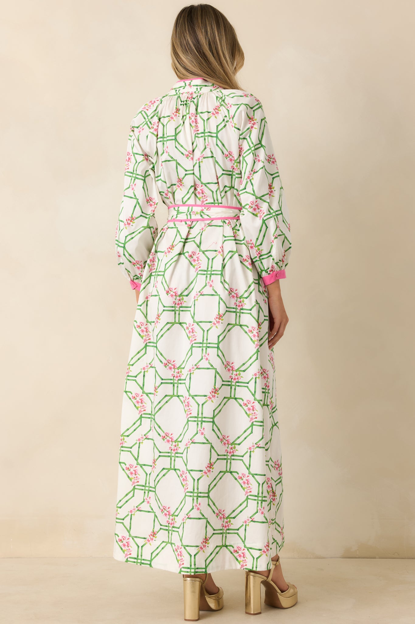Rear view of the white cotton maxi dress featuring long sleeves, adjustable waist tie, and flowing maxi-length skirt.