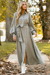 Front view of this dress that features a collared neckline, functional buttons down the front, long sleeves with buttoned cuffs, two functional pockets, and adjustable self-tie belt.
