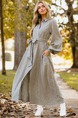 Full body view of this dress that features a collared neckline, functional buttons down the front, long sleeves with buttoned cuffs, two functional pockets, and adjustable self-tie belt.