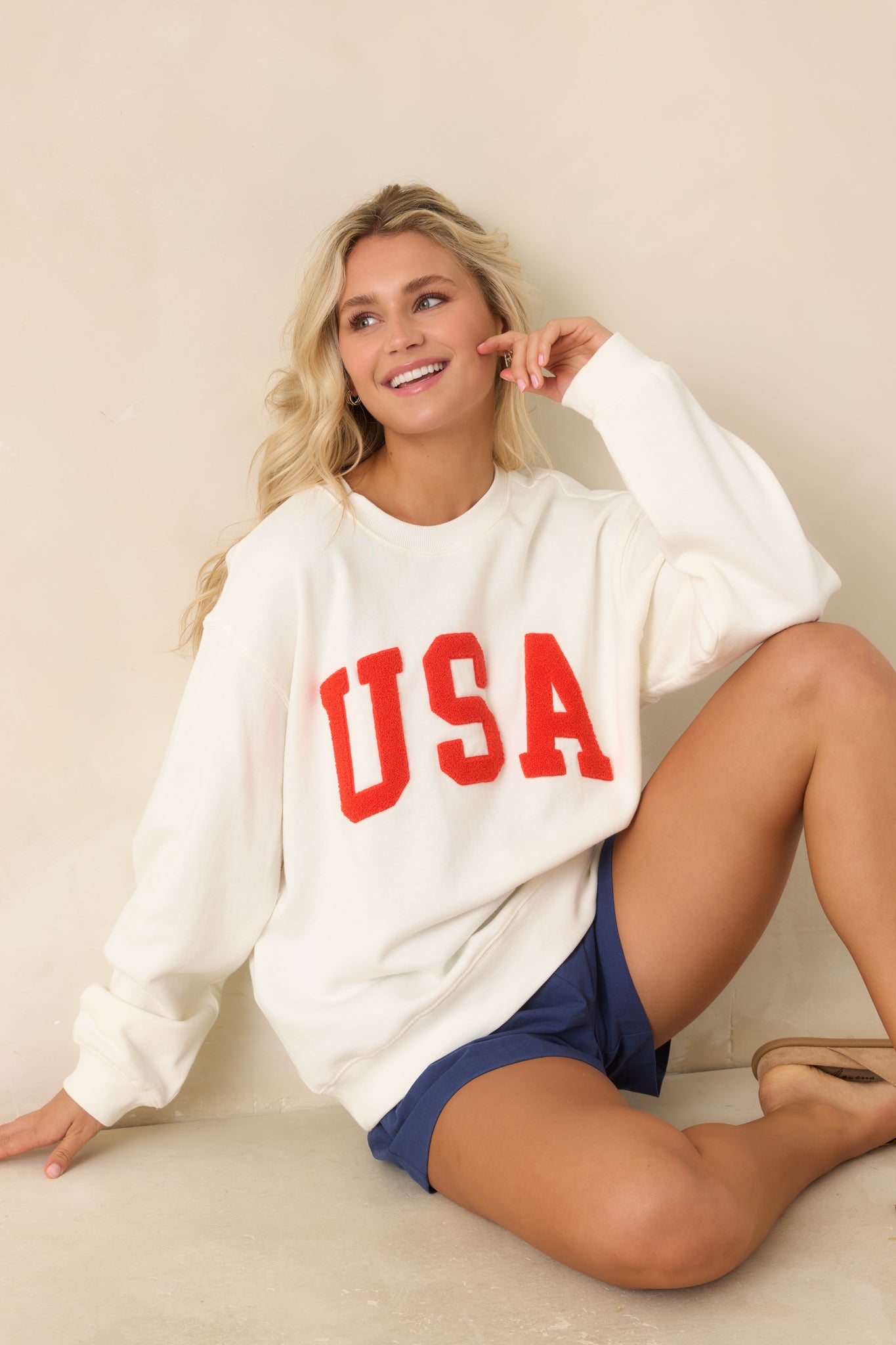Ivory cotton sweatshirt with soft textured “USA” lettering centered on the chest, styled in a relaxed boyfriend silhouette with ribbed cuffs and hem.