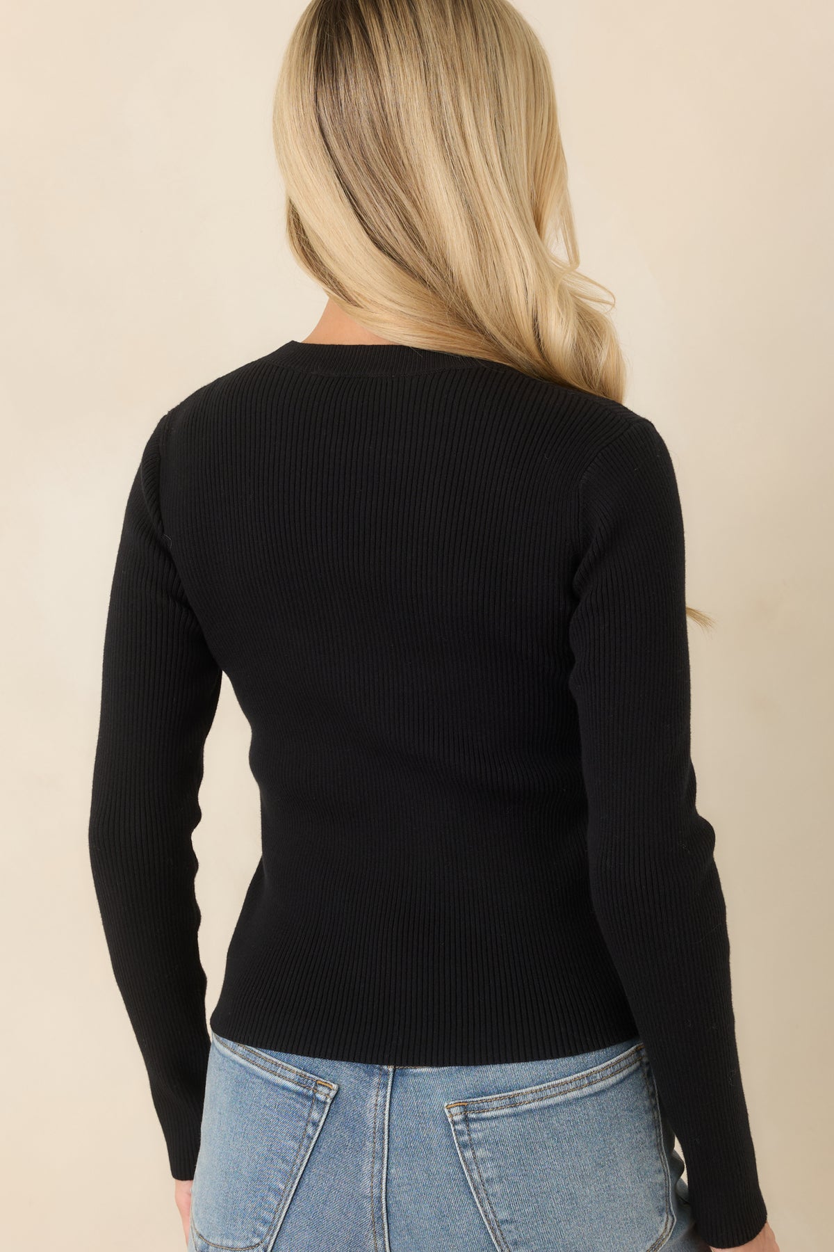 Rear view of the black ribbed knit top showing its fitted silhouette, long sleeves, and classic crew neckline.