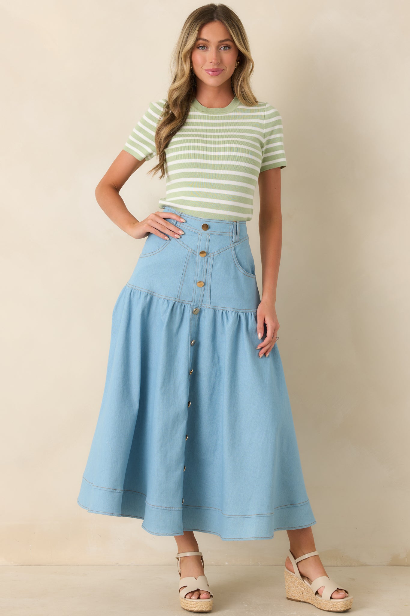 High-rise light wash denim maxi skirt with tiered panels and button-down front, designed with structured waistband and classic pocket detailing.