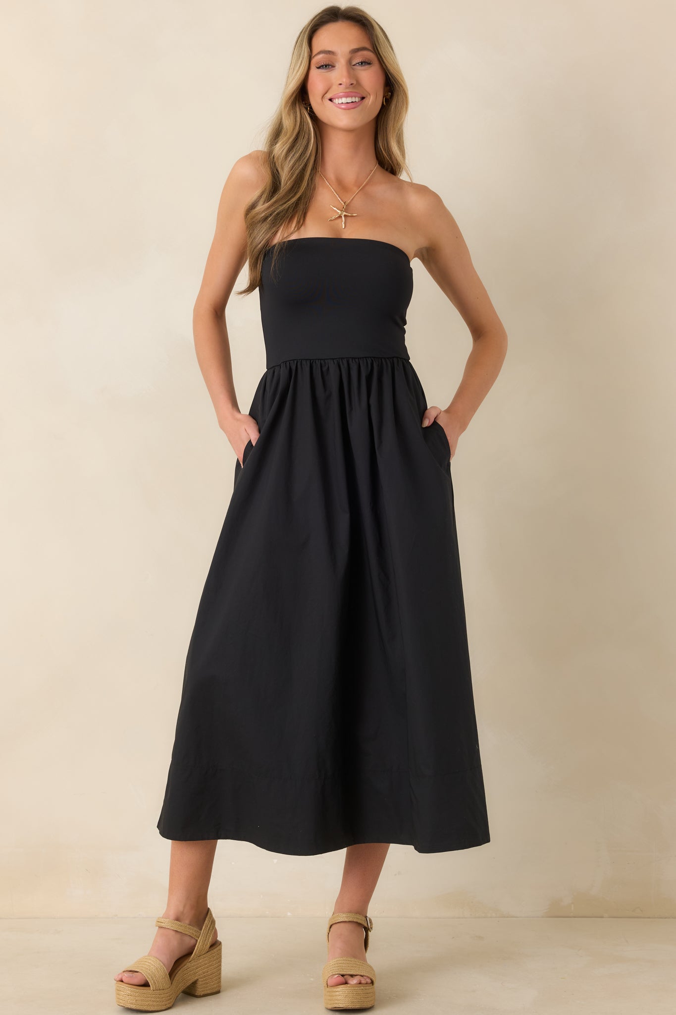 Full view of black midi dress highlighting the balanced shape between structured top and gathered skirt.
