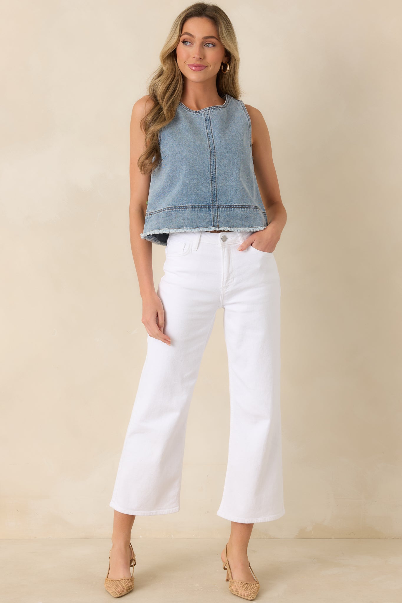 Light wash denim sleeveless top, with a structured silhouette, round neckline, and slightly cropped length.