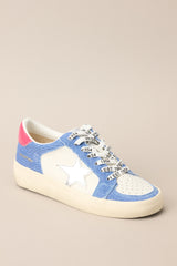 Angled front view of these sneakers that feature a rounded toe, functional laces, medium wash denim trim, silver stars, and neon pink detailing.