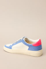Inner-side view of these sneakers that feature a rounded toe, functional laces, medium wash denim trim, silver stars, and neon pink detailing.