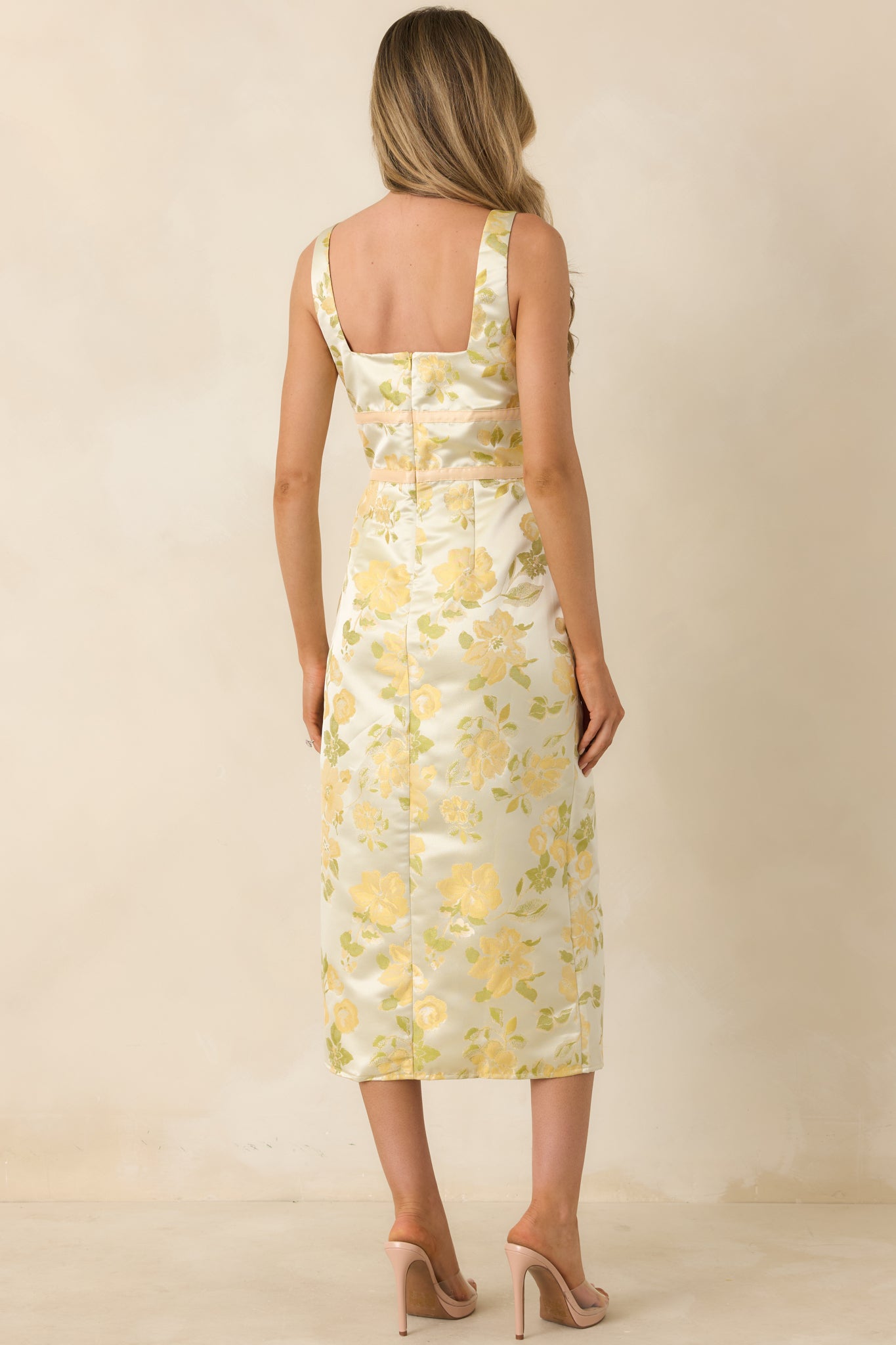 Rear view of yellow floral dress with wide straps and fitted silhouette through the back.