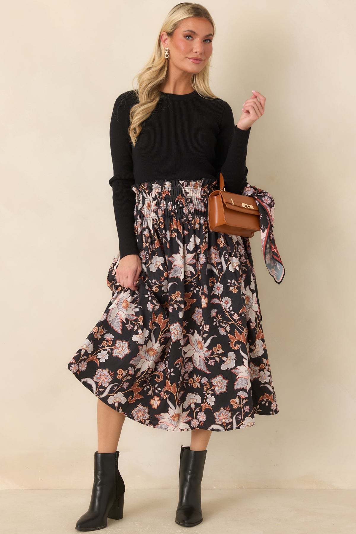The black floral cotton midi skirt features a colorful botanical pattern and a full, gathered A-line shape beneath its wide smocked waistband.