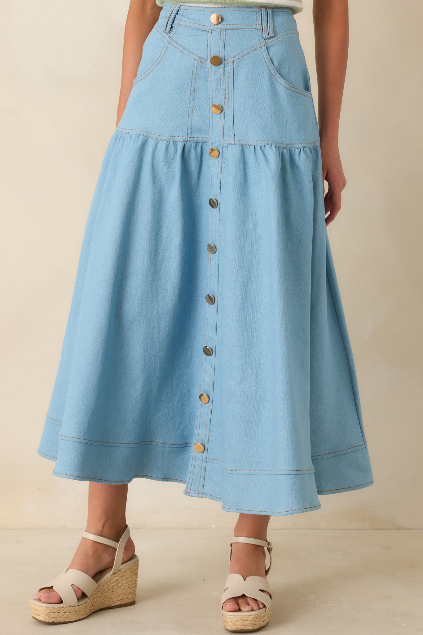 Cropped view of tiered denim maxi skirt with contrast stitching and softly flared panel construction.