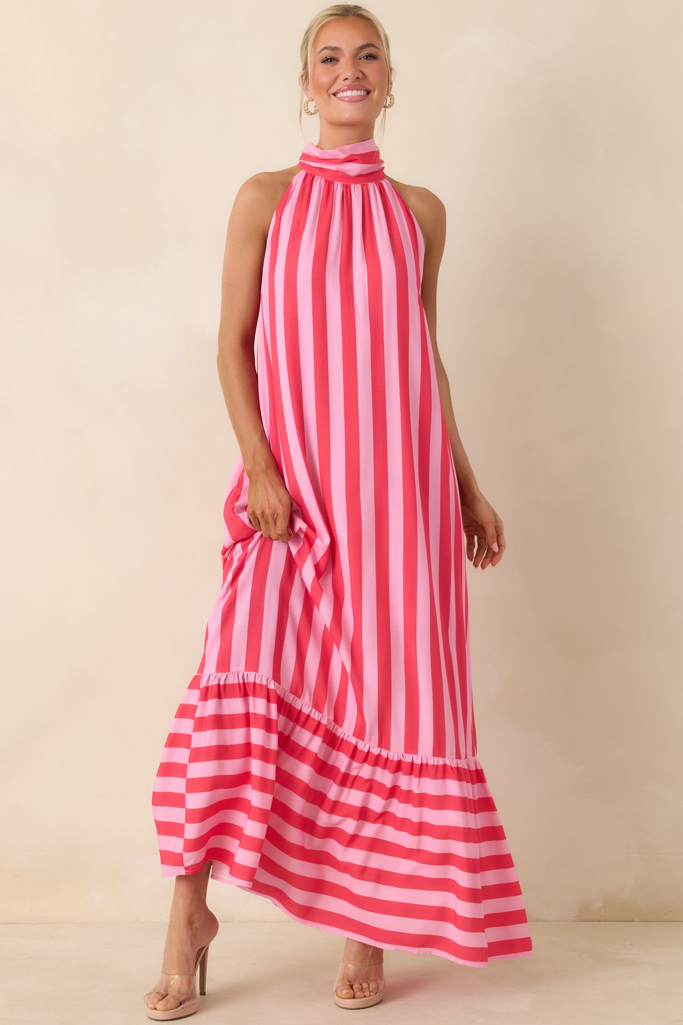 Halter dress with bold fuchsia and light pink stripes, finished with a tiered skirt and playful movement.