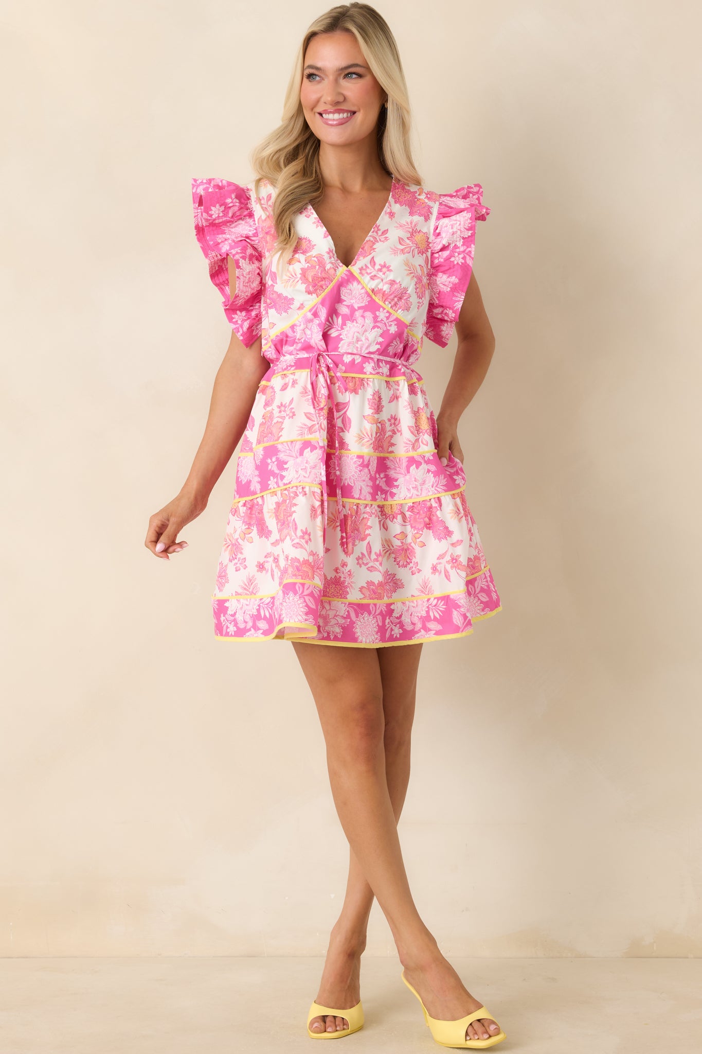 Pink floral mini dress with flutter sleeves and tiered skirt detailing.