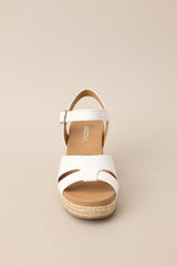 Front view of these espadrille sandals with white straps over the top, ankle strap with buckle closure, and wedged heel.