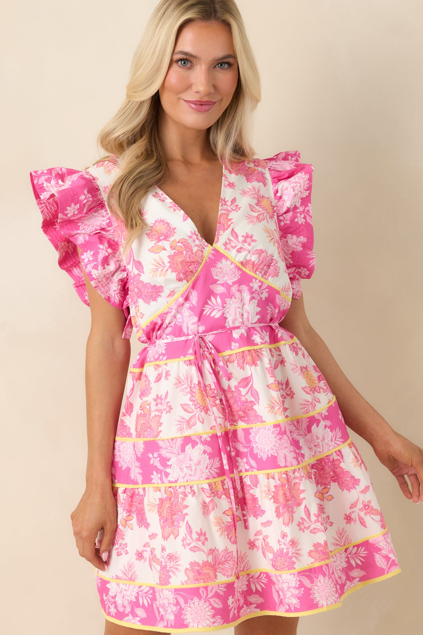 Pink floral dress highlighting V-neckline and flutter sleeve detail.