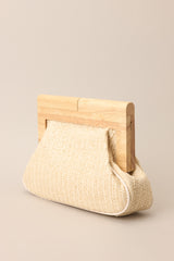 Angled view of this ivory rattan clutch with a wooden handle.