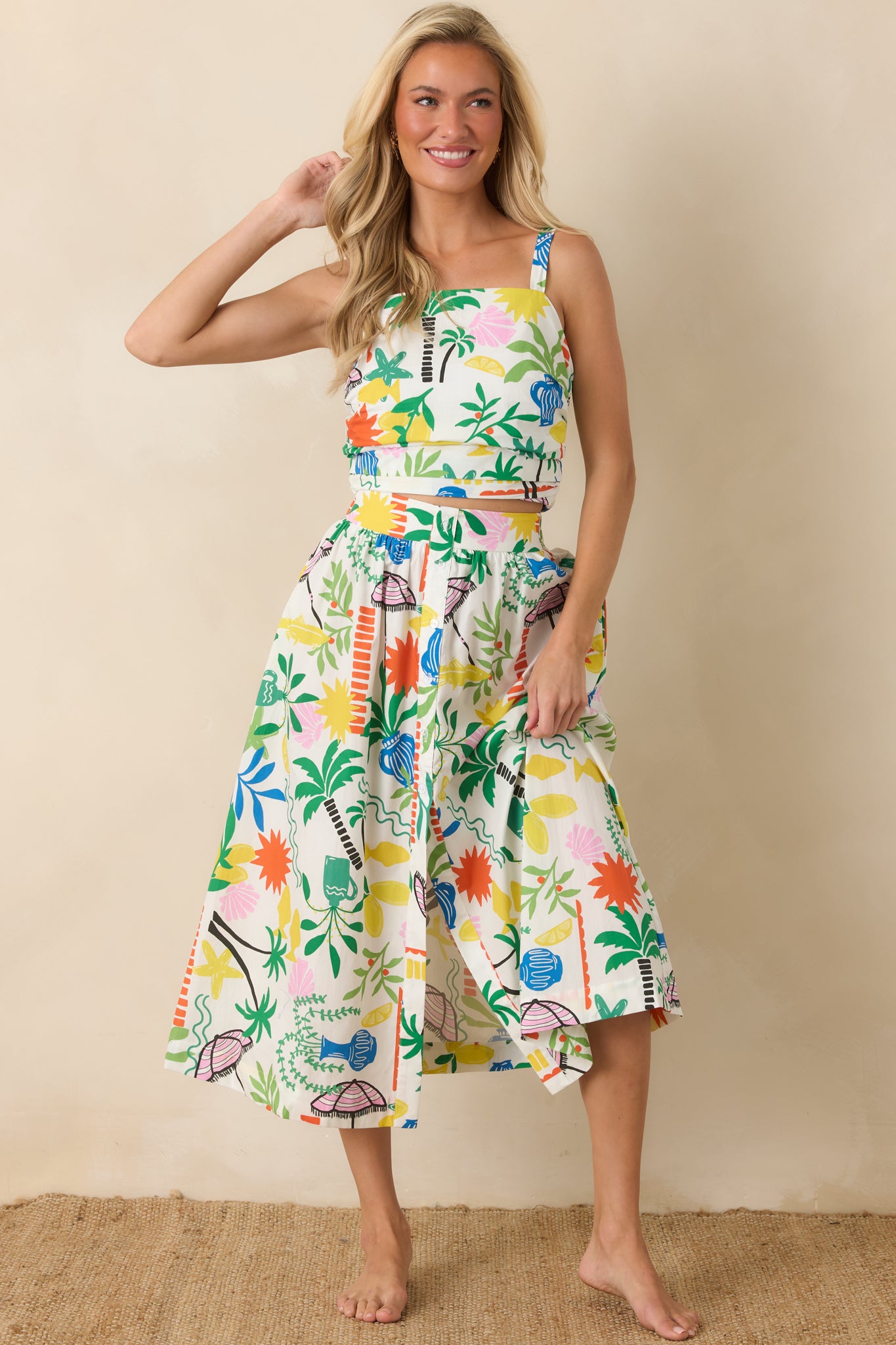 White multi crop top featuring a colorful coastal resort print, straight neckline, and wide shoulder straps.
