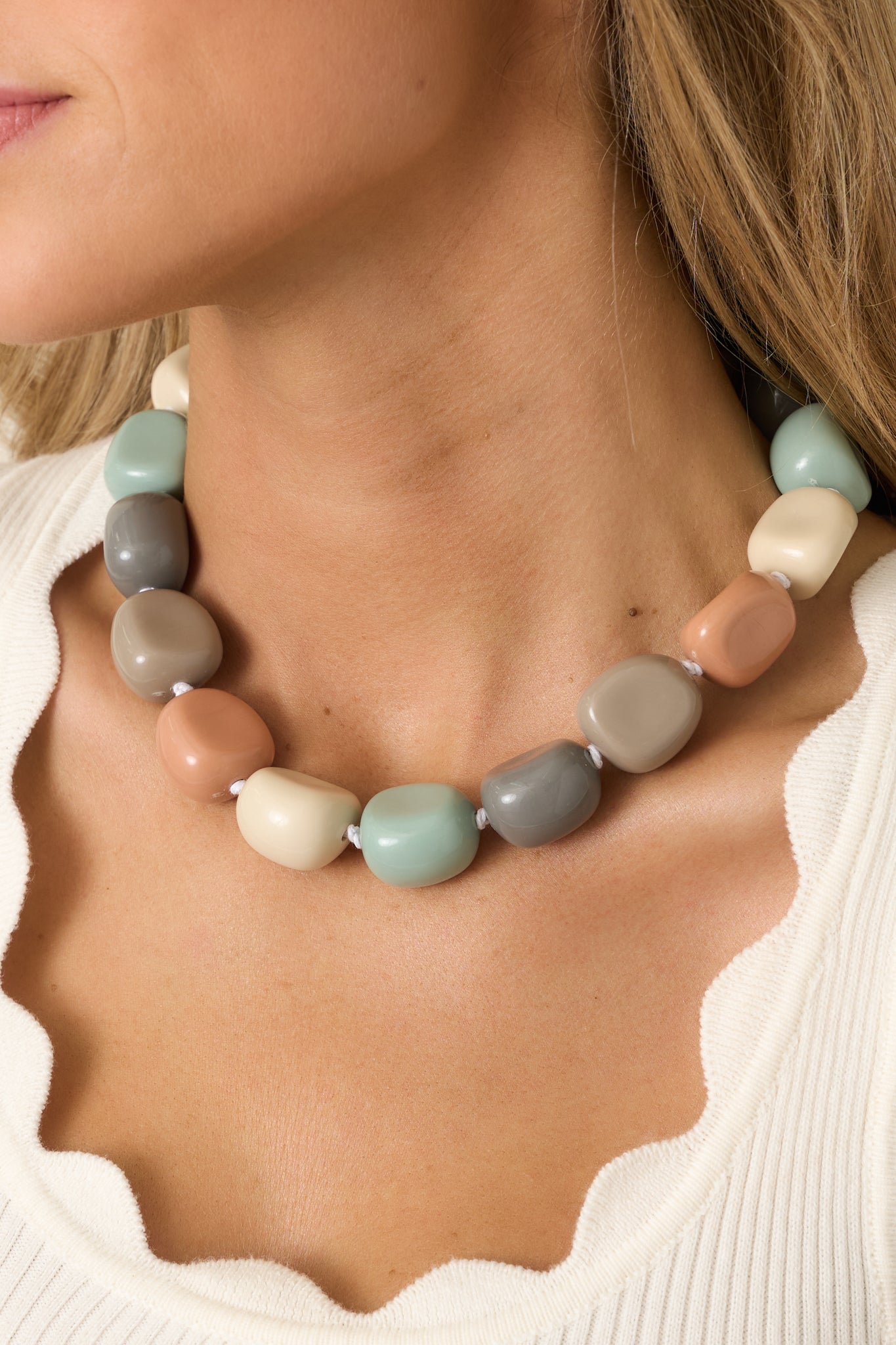 Detailed close-up of beaded necklace highlighting smooth rounded beads in sage, blush, sand, and grey with a bold chunky design.