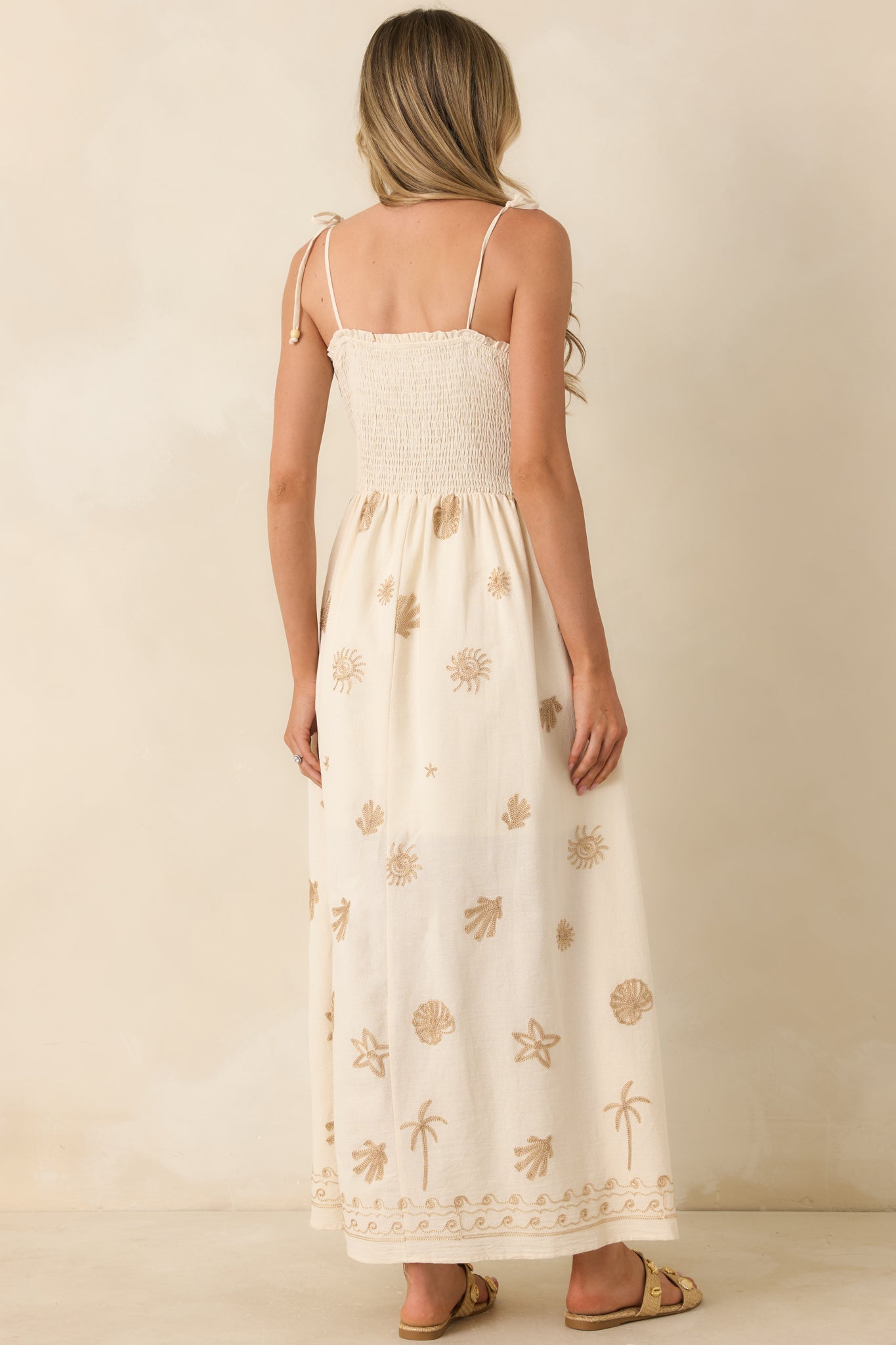 Rear view of the ivory maxi dress showcasing the smocked elastic back panel and adjustable tie straps.