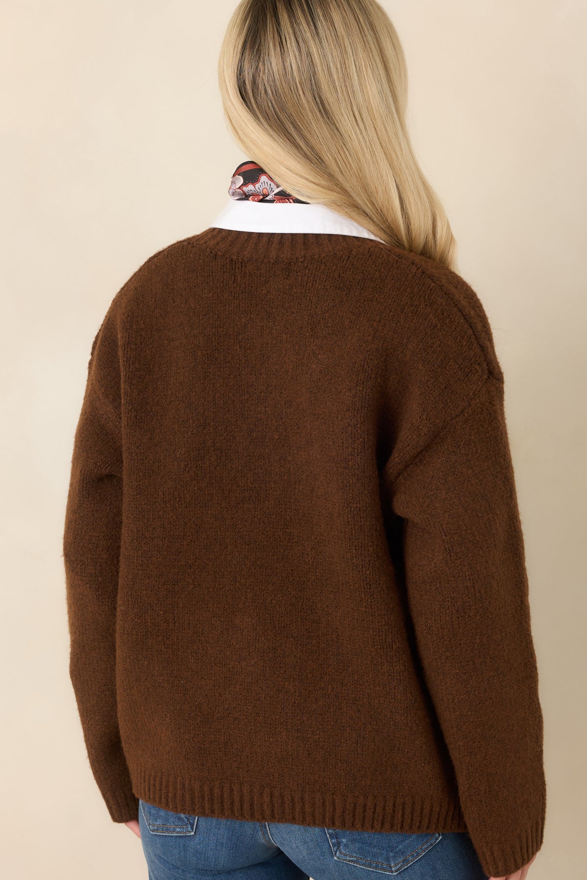 Rear view of the chestnut brown knit cardigan showing its relaxed shape, dropped shoulders, long sleeves, and ribbed hem.