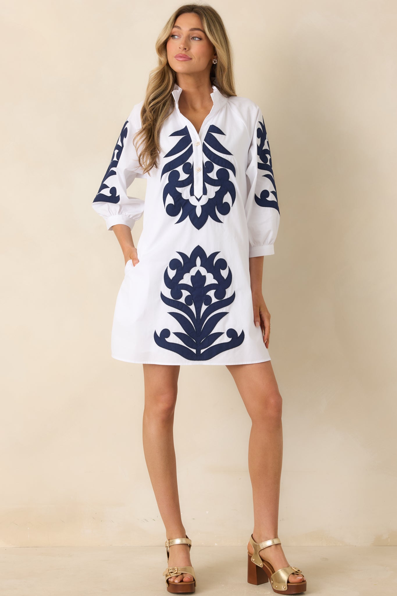 Crisp white mini dress featuring navy accents and three-quarter sleeves.