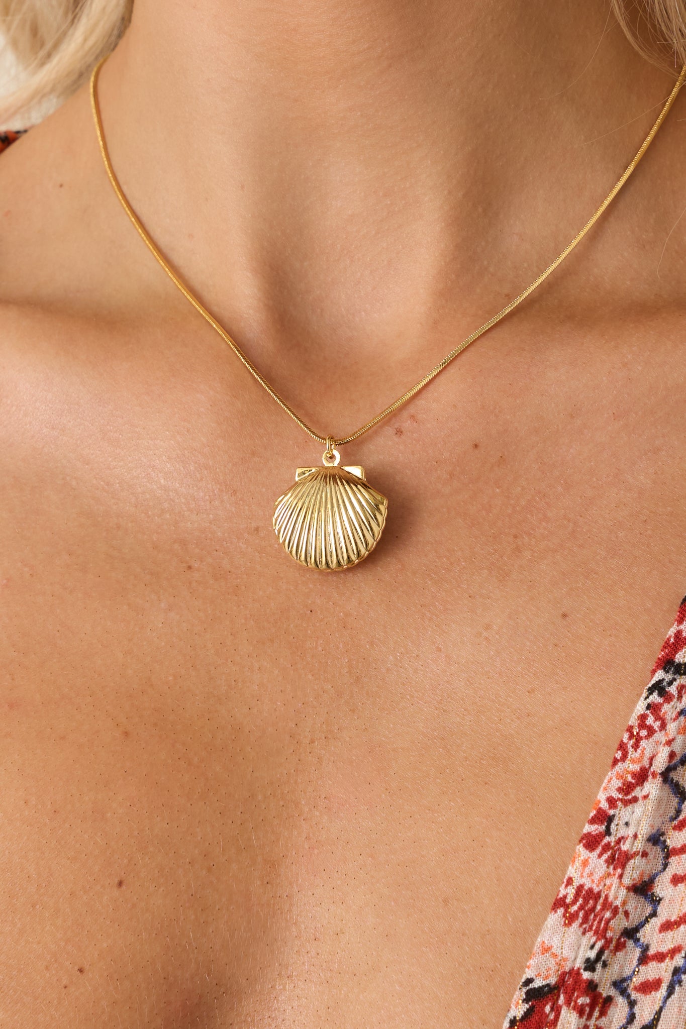 Cropped view highlighting the shell pendant charm and fine chain detailing with a subtle shine.