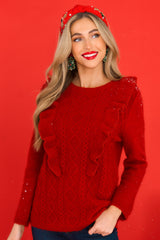 Front view of this sweater that features a scoop neckline, ruffles around the bust, and a cable knit detail on the front.