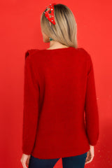 Back view of this sweater that features a scoop neckline, ruffles around the bust, and a cable knit detail on the front.