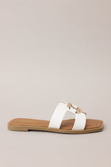 Side view of these white sandals with square toe, slip-on design, strap with cutouts and gold accent piece over foot.