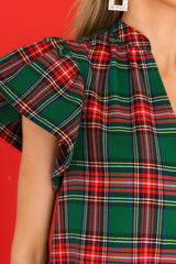 Close up view of this top that features a v-neckline, functional buttons down the front, flutter sleeves, and an all over plaid design.