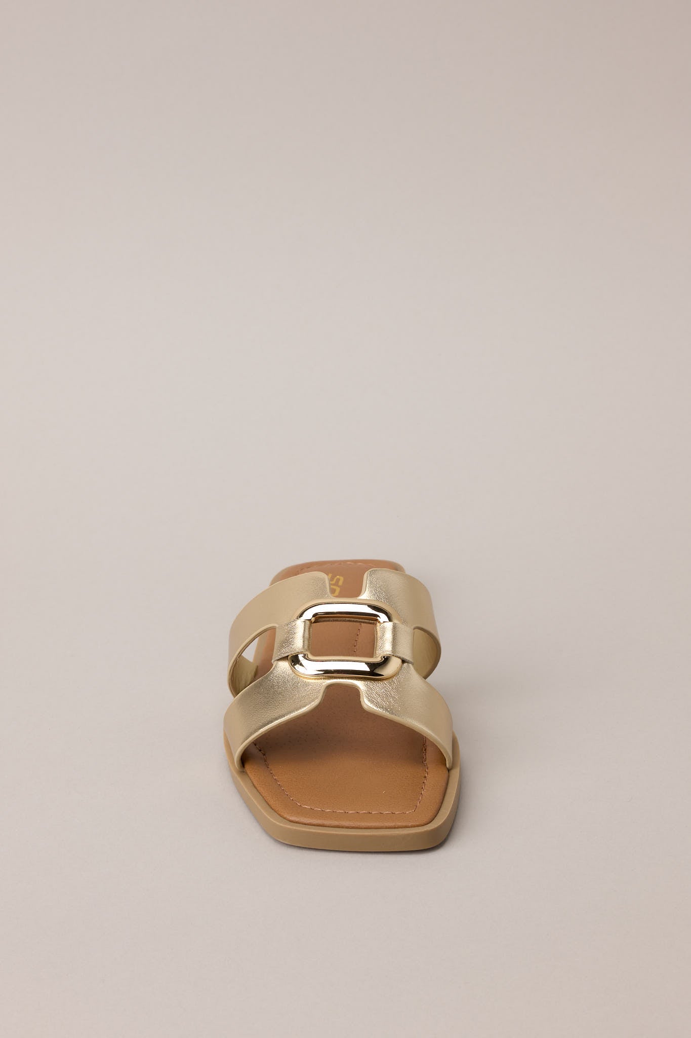 Gold square-toe sandals displayed against a beige background, emphasizing the slip-on design and cutout strap.