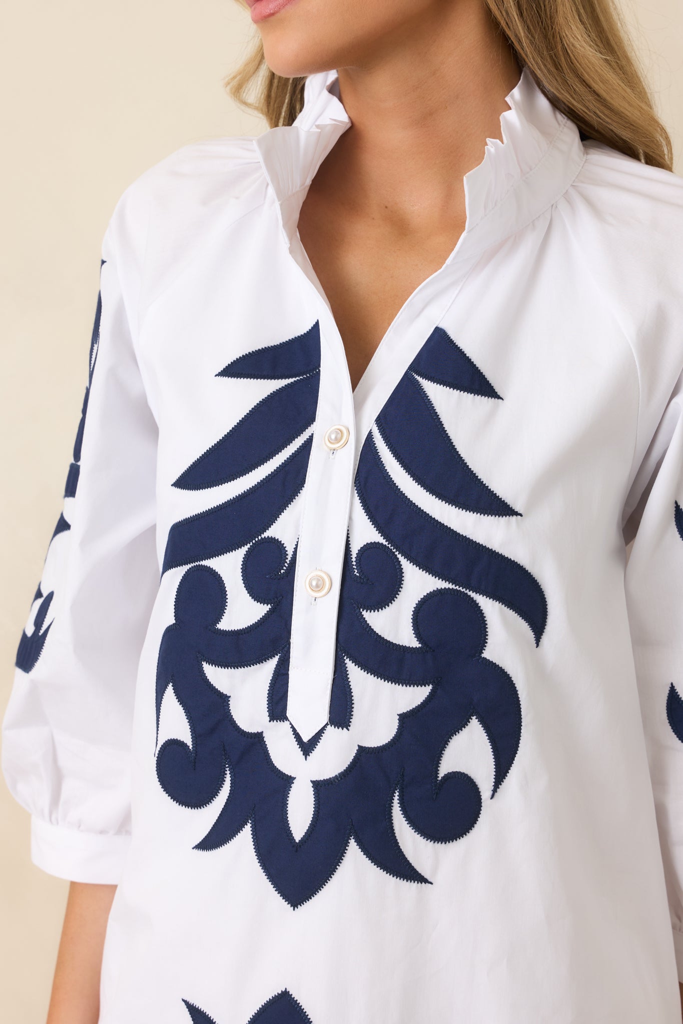 Close-up of split neckline with button accents and navy contrast trim.