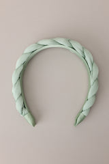 Flat front view of this headband that features a thick, soft material, and a braided texture. 