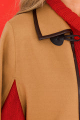 Close up view of this poncho that features functional pockets, faux leather trim, and button closure.