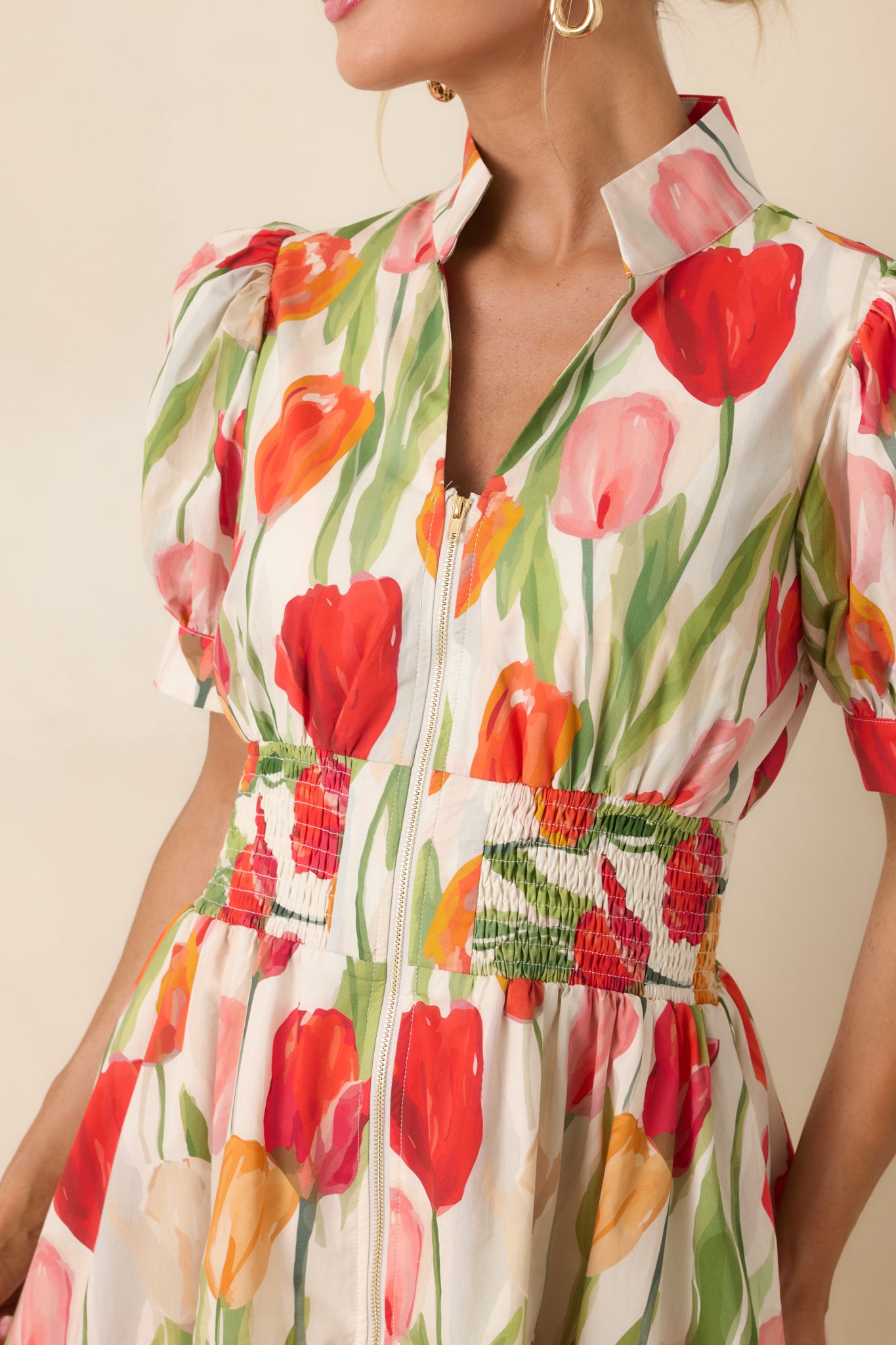 Close view of red and multi-color tulip print on ivory cotton with zipper detail and smocked waist texture.