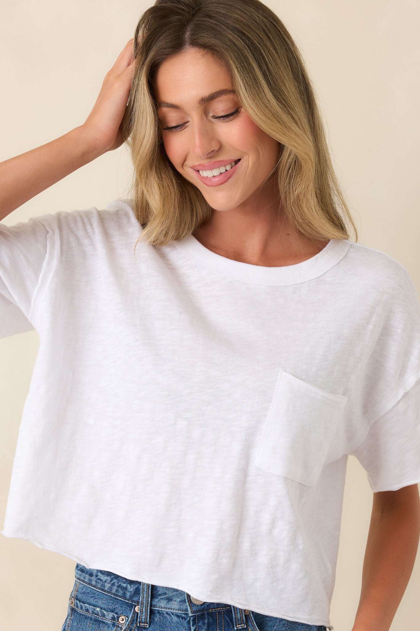 Close view of crew neckline and front patch pocket on white cotton tee.