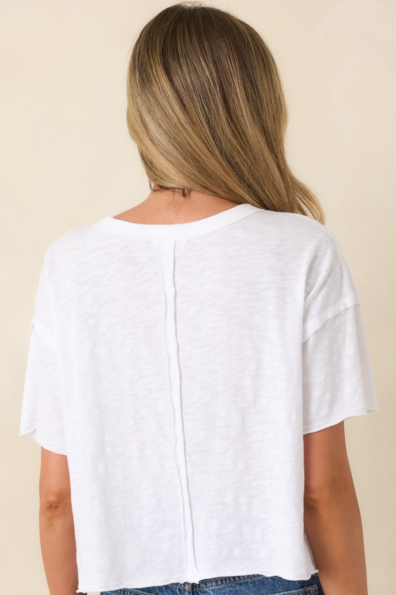 Rear view of white relaxed-fit tee with crew neckline and slightly cropped silhouette.