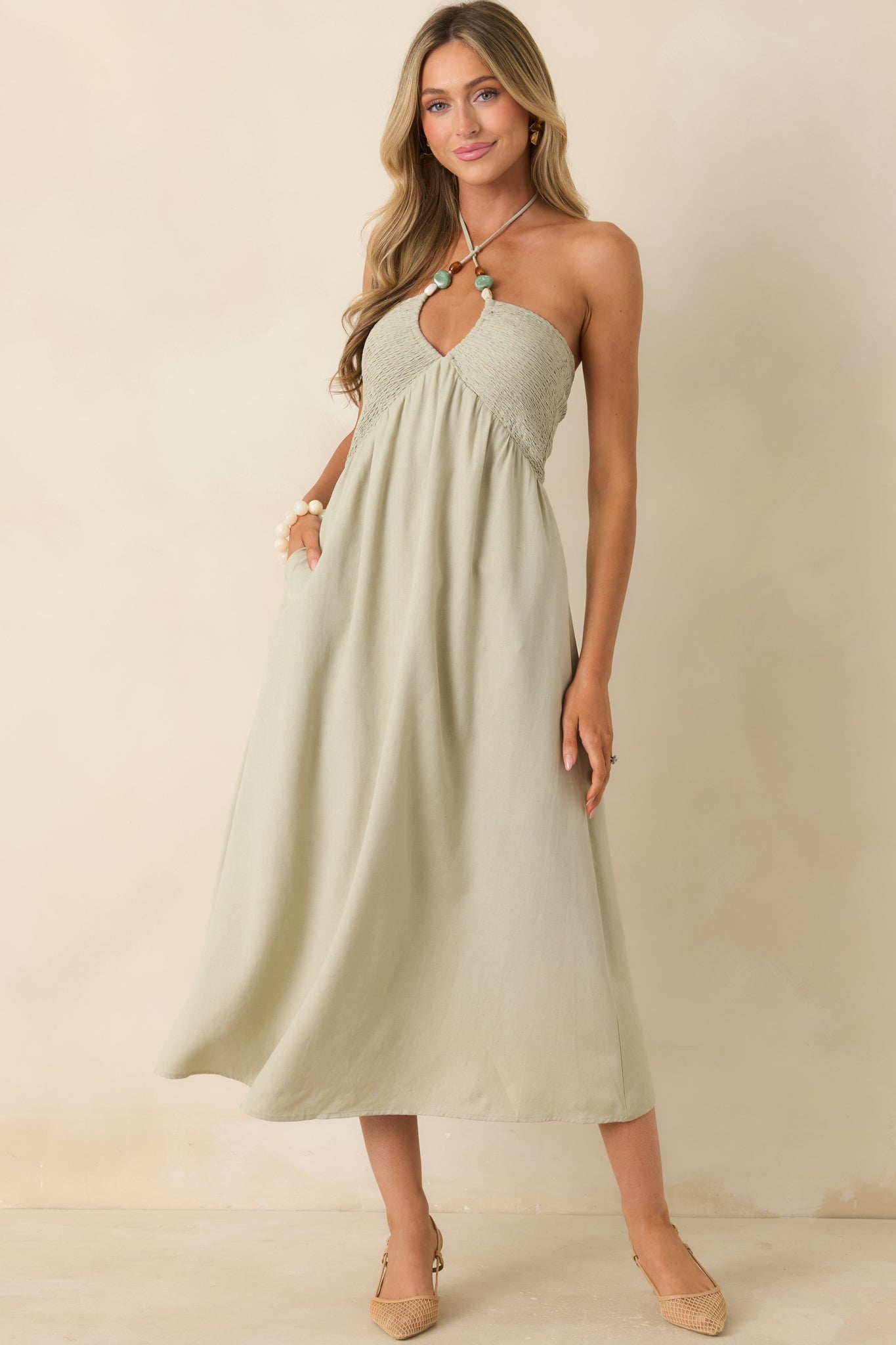 Flowing sage midi dress featuring a halter-style neckline and soft gathered skirt movement.