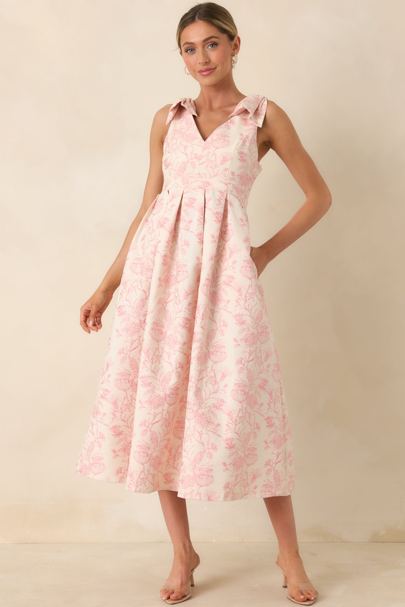 Front-facing view highlighting the V-neckline and voluminous pleated skirt of a pink floral midi dress.