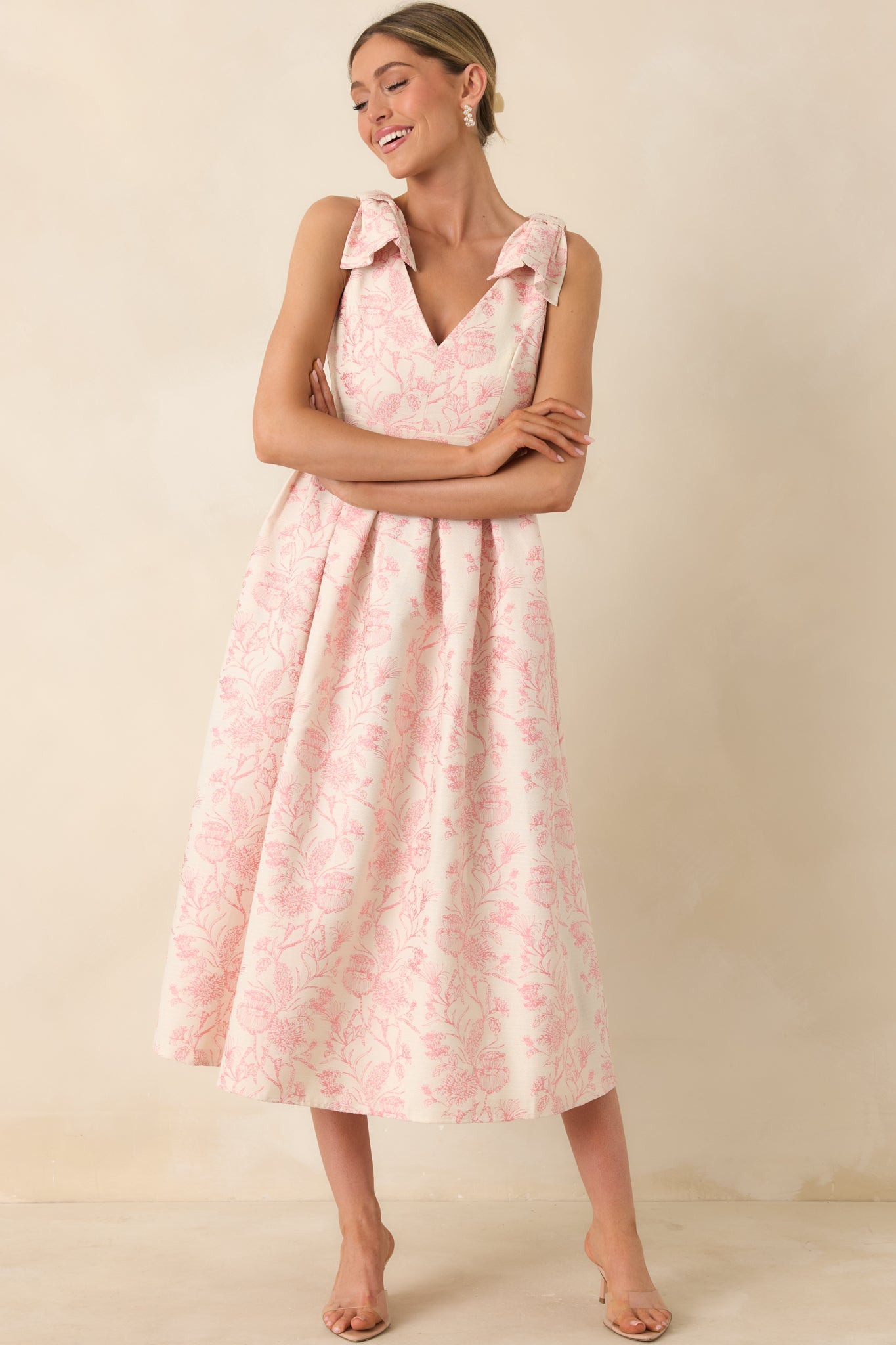 Pink printed midi dress with bow-tie shoulders and structured fabric, featuring a twirl-worthy flared skirt.