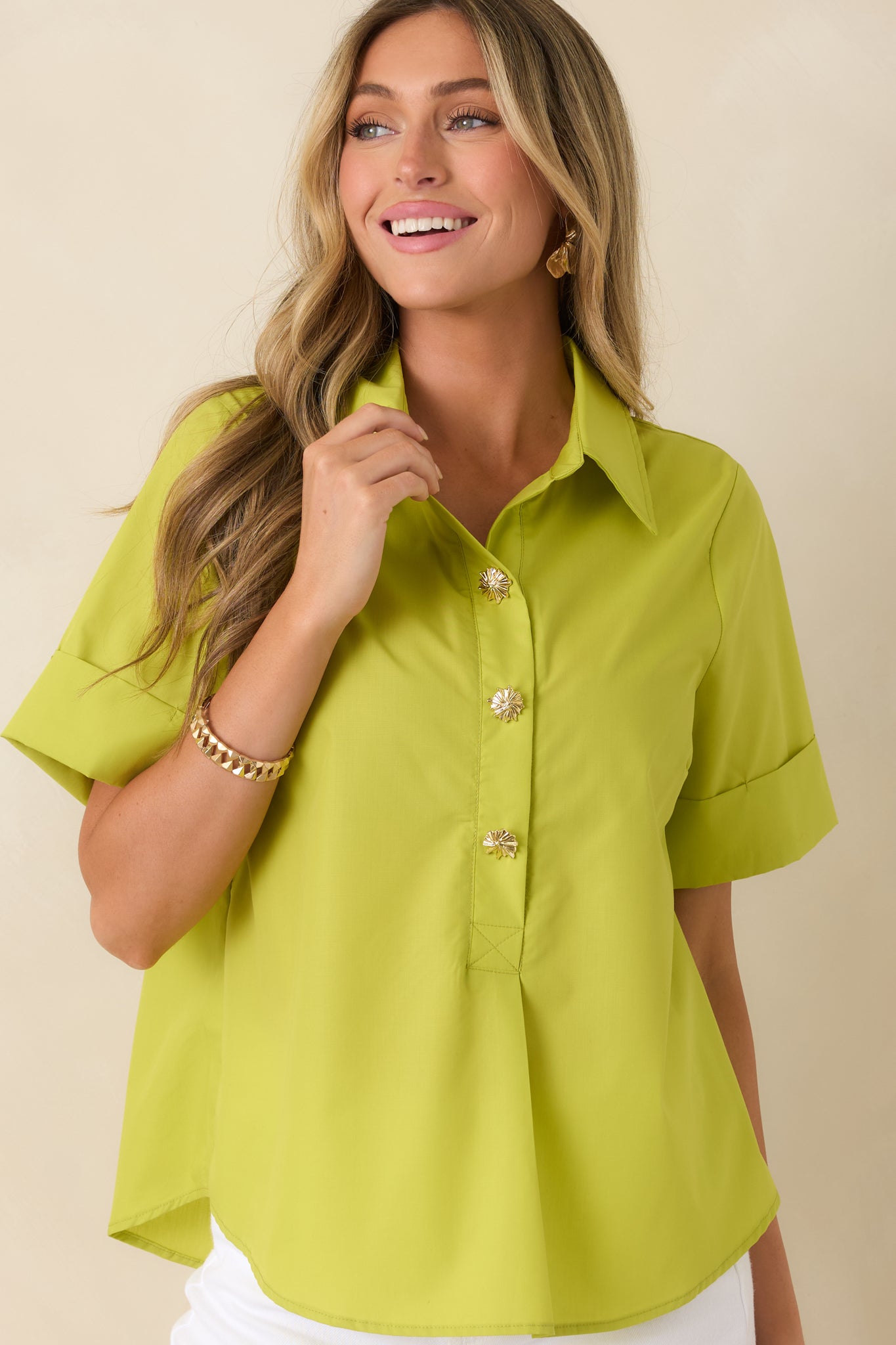 Close view of the collared neckline and partial button placket highlighted by statement button detailing.