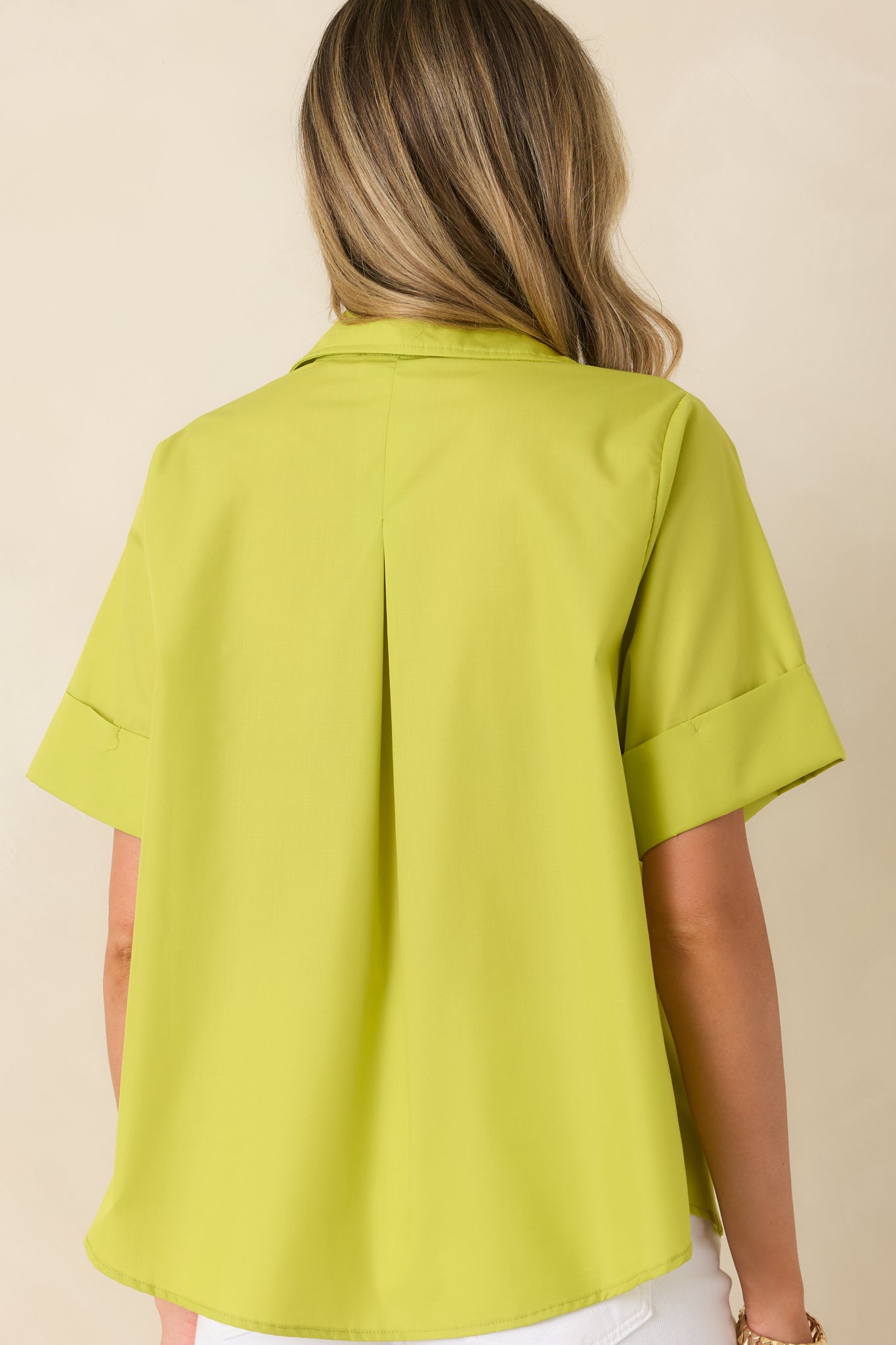 Back view of the chartreuse green blouse featuring a subtle back pleat, relaxed boxy silhouette, and slightly rounded hemline.

