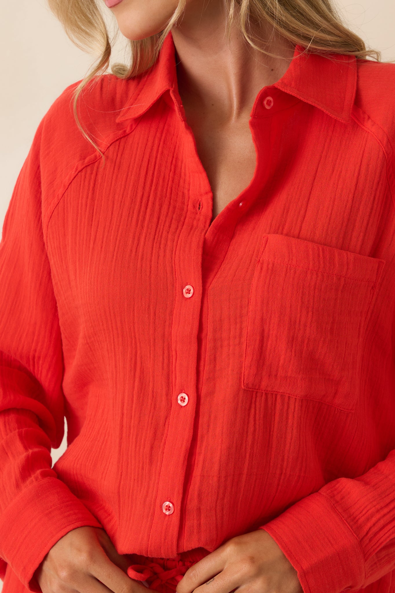 Detailed view of the poppy red cotton gauze fabric highlighting the button-front closure, collared neckline, and textured weave.