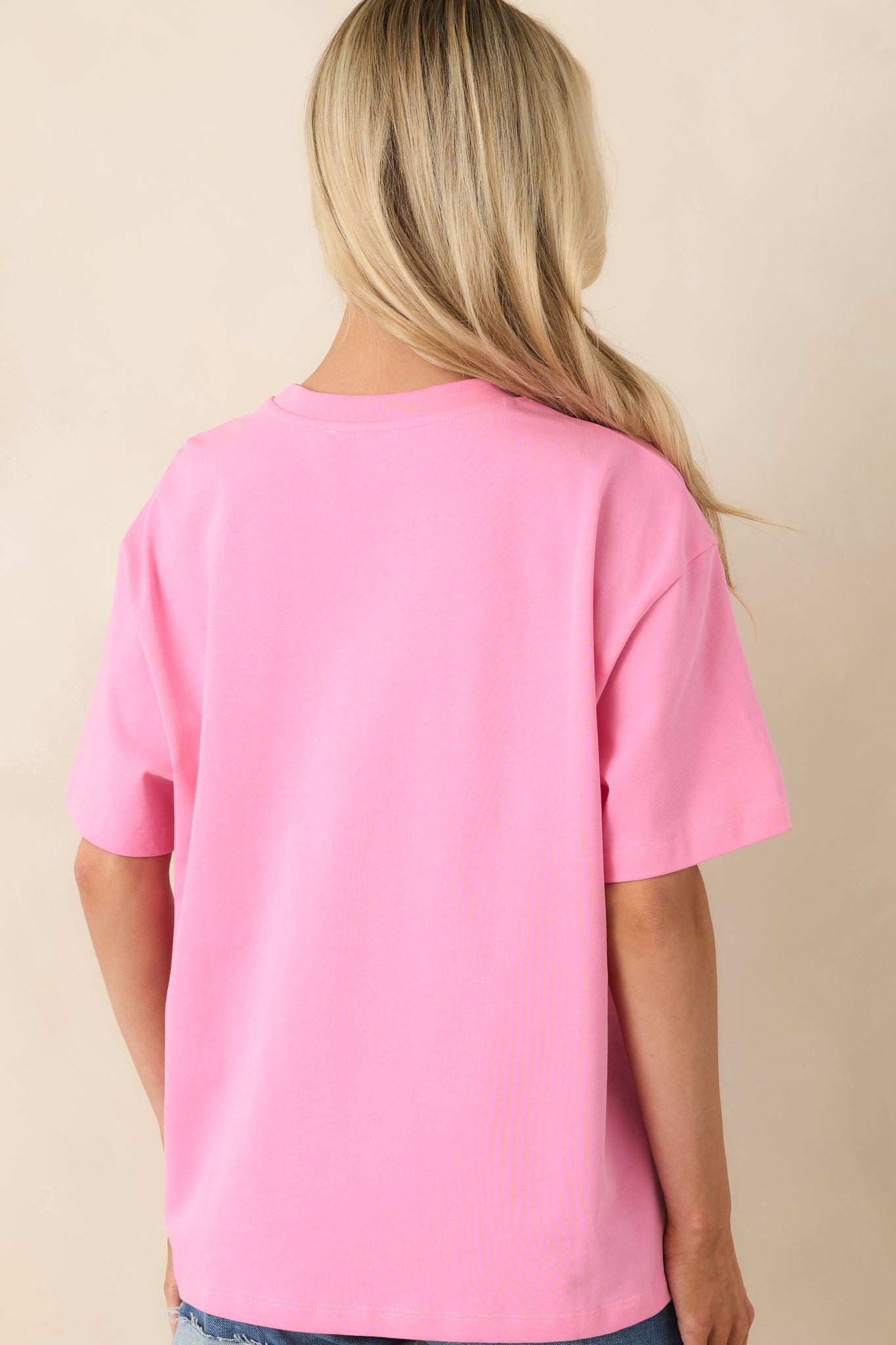 Rear view of vibrant pink tee with relaxed oversized fit and smooth cotton finish.
