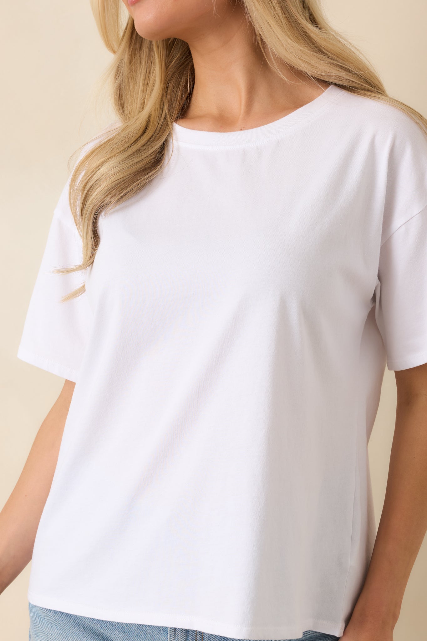 Detailed view of soft white cotton fabric and clean neckline stitching on the tee.
