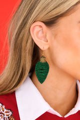 Model shown wearing earrings that feature beaded light bulbs, gold detailing, and fish hook fastening. 