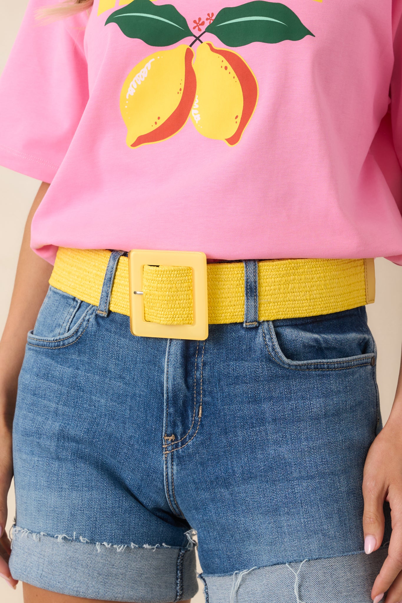 Cropped view of yellow woven elastic belt featuring a square acrylic pin buckle.