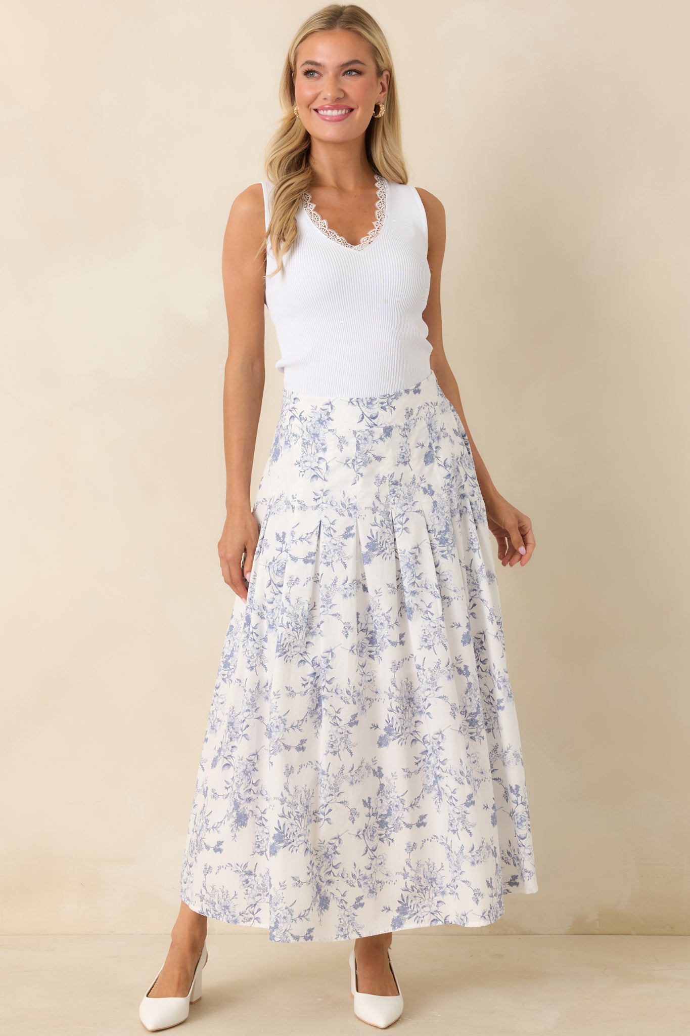 Woman wearing a white sleeveless top and floral skirt against a beige background