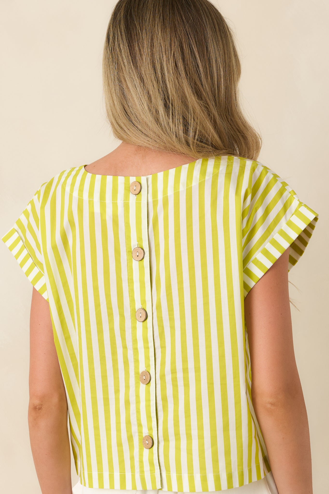 Back view of the green striped cotton top featuring functional button closures, structured silhouette, and short cuffed sleeves.

