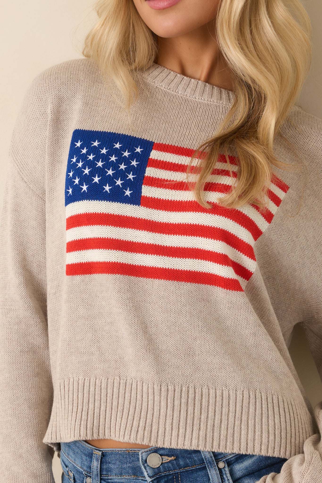 Detailed view of the knit American flag graphic and ribbed trim on the heather sweater.