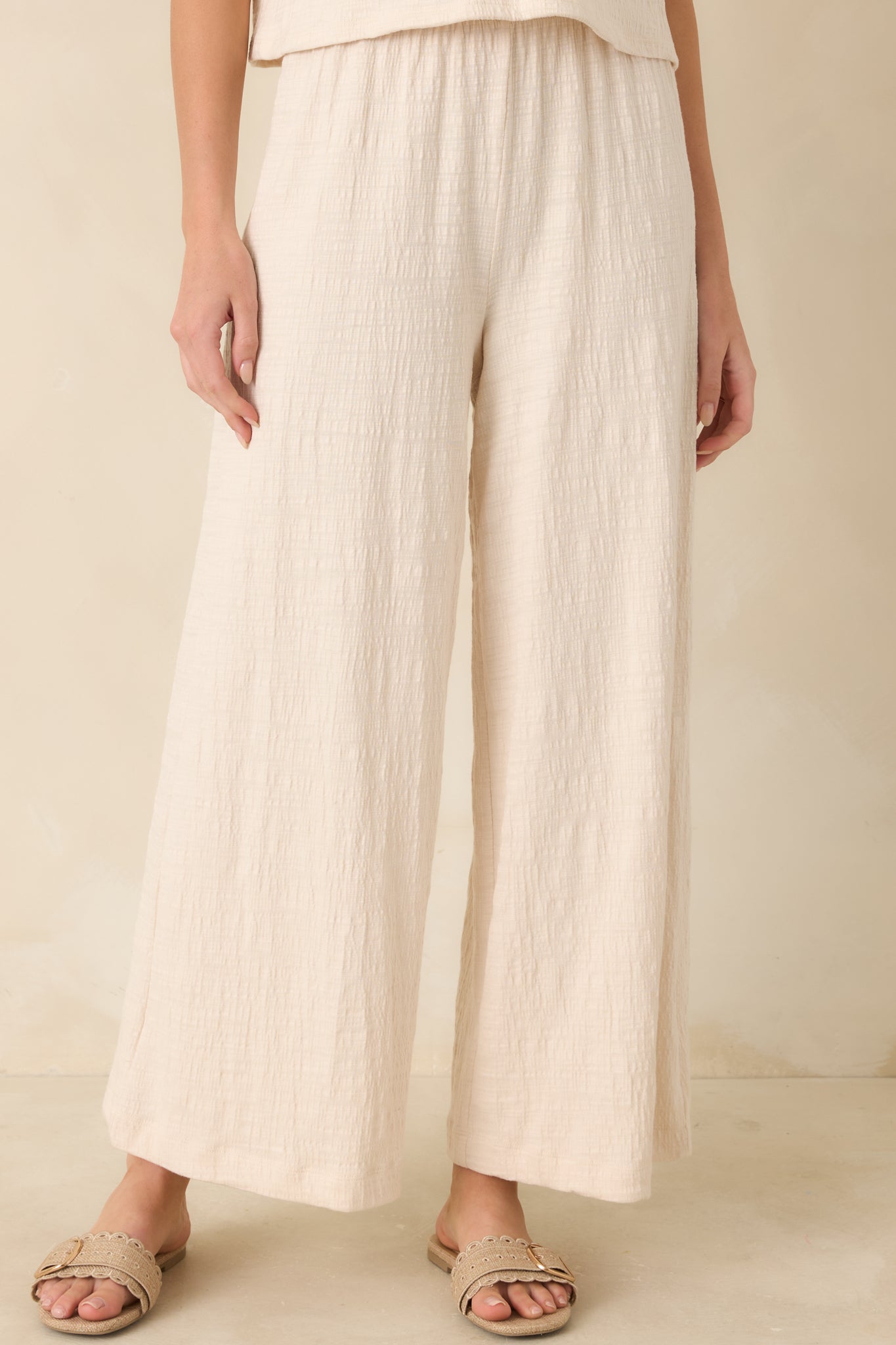 Close view of elastic waistband on ivory high-rise wide-leg pants.